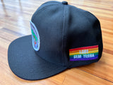 BONÉ PRETO LGBT - Aba interna com arco-íris, escrita “LGBT” branco e bandeira LGBT SEM TERRA na lateral